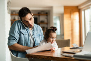 Photo of dad working from home with kids doing remote schooling.